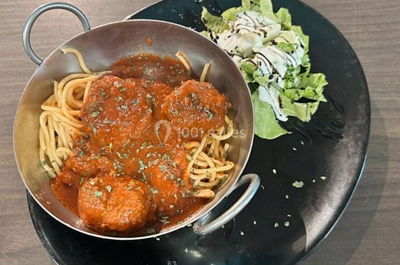 Assiette avec des spaghettis et boulettes de viande en sauce tomate, accompagnée d'une salade verte avec vinaigrette.