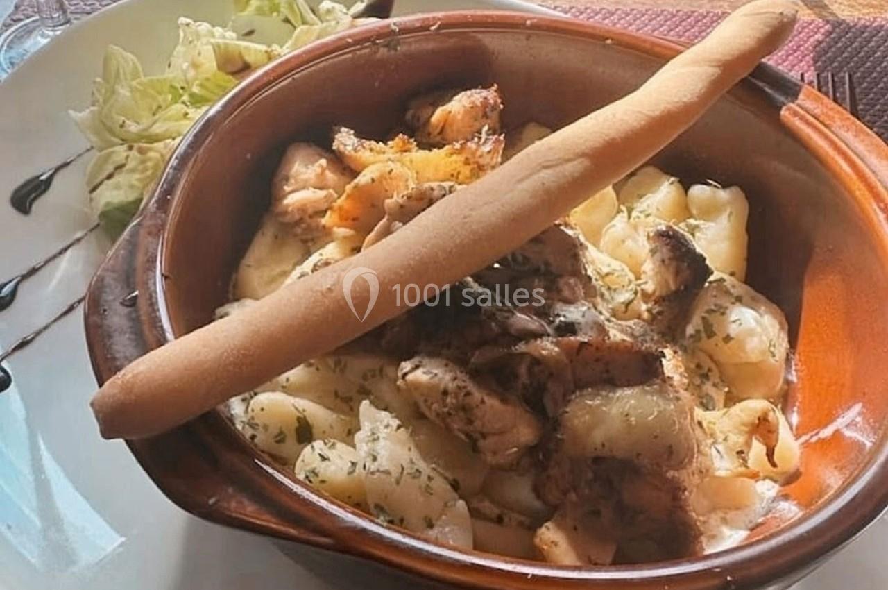 Plat de pâtes crémeuses avec morceaux de viande, herbes, grissini et salade verte en accompagnement.