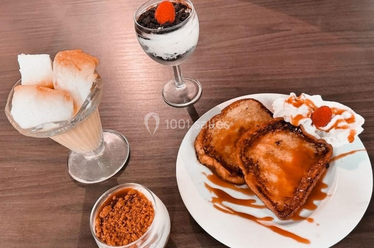 Assortiment de desserts comprenant pain perdu, crème glacée, verrines et chantilly sur une table en bois.