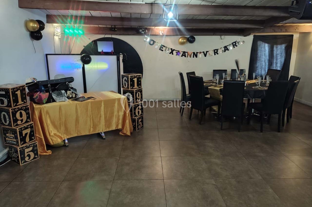 Salle décorée pour un anniversaire avec table dressée, guirlande murale, cubes décoratifs et projecteur.