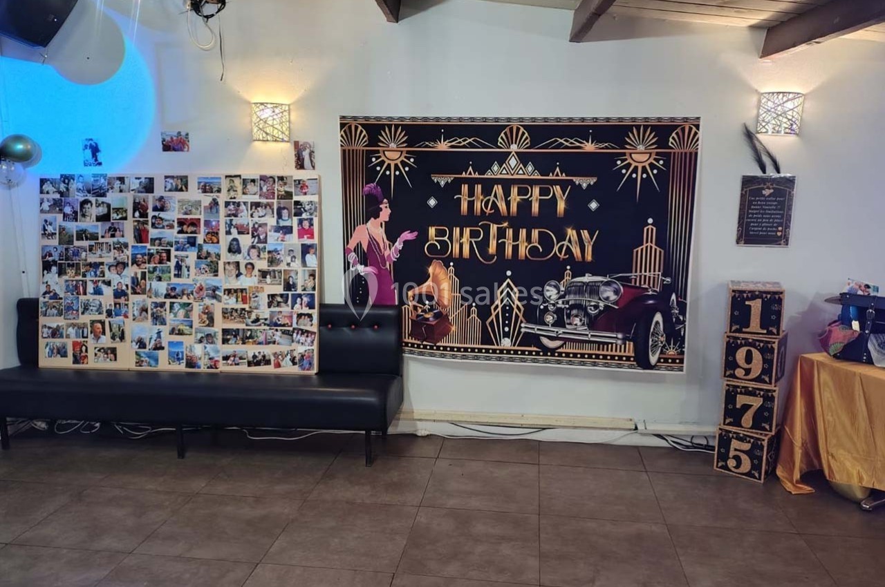 Décoration d'anniversaire avec une affiche rétro ’Happy Birthday’, un mur de photos et des éléments vintage.