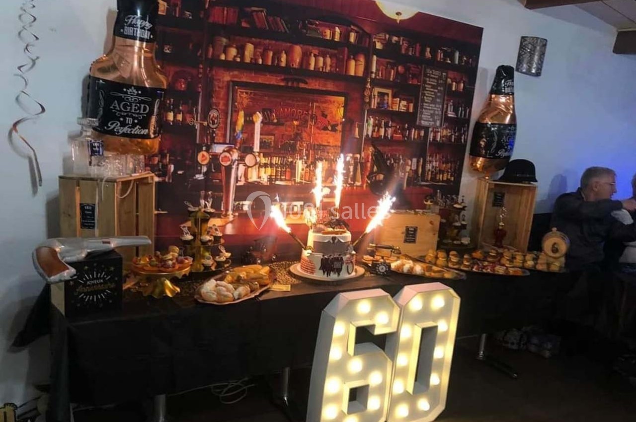 Table décorée pour un 60e anniversaire avec gâteau, bougies étincelantes, nourriture et décorations sur le thème d'un bar.