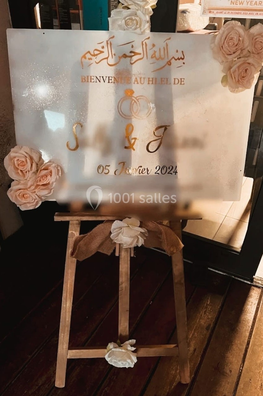 Panneau de bienvenue pour un mariage, décoré de roses et posé sur un chevalet en bois.