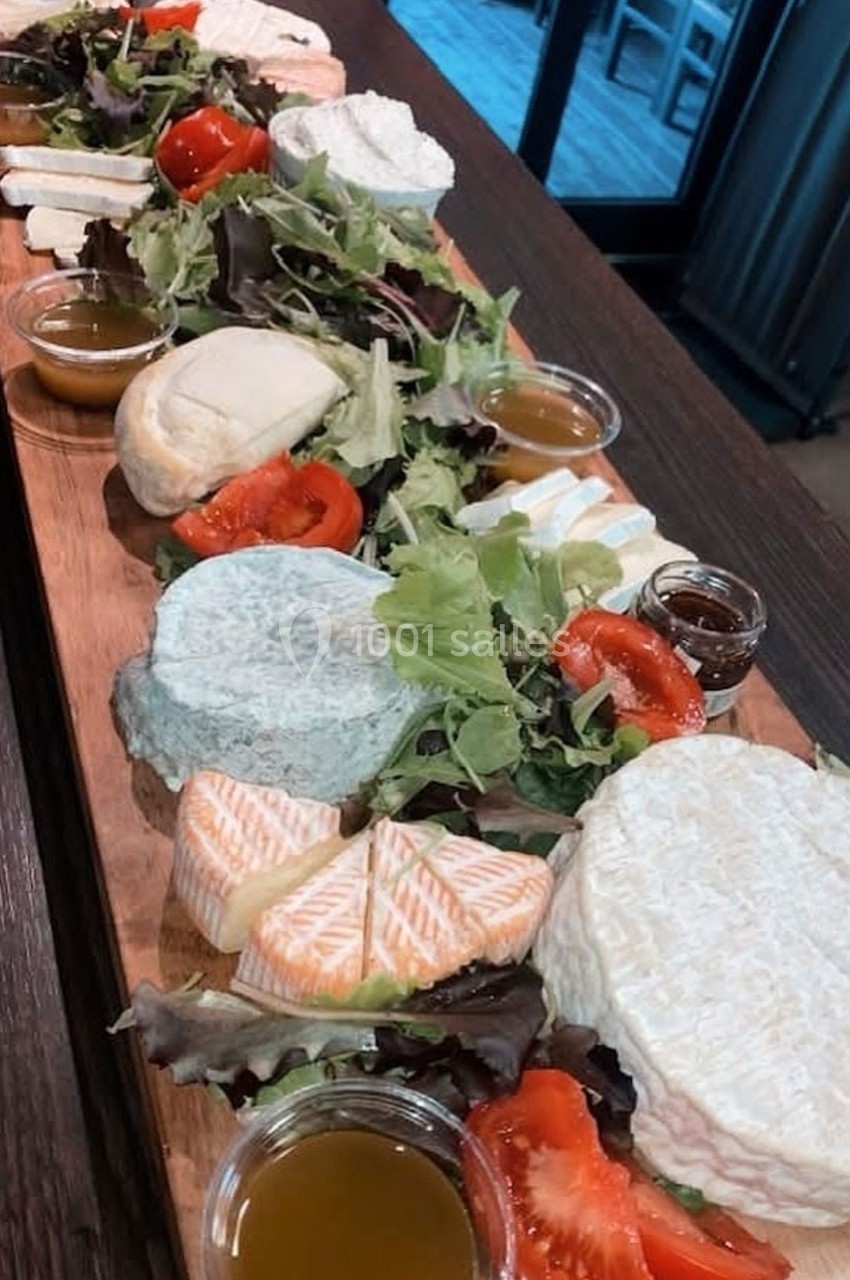 Plateau en bois garni de fromages variés, salades, tomates et petites coupelles de sauce.