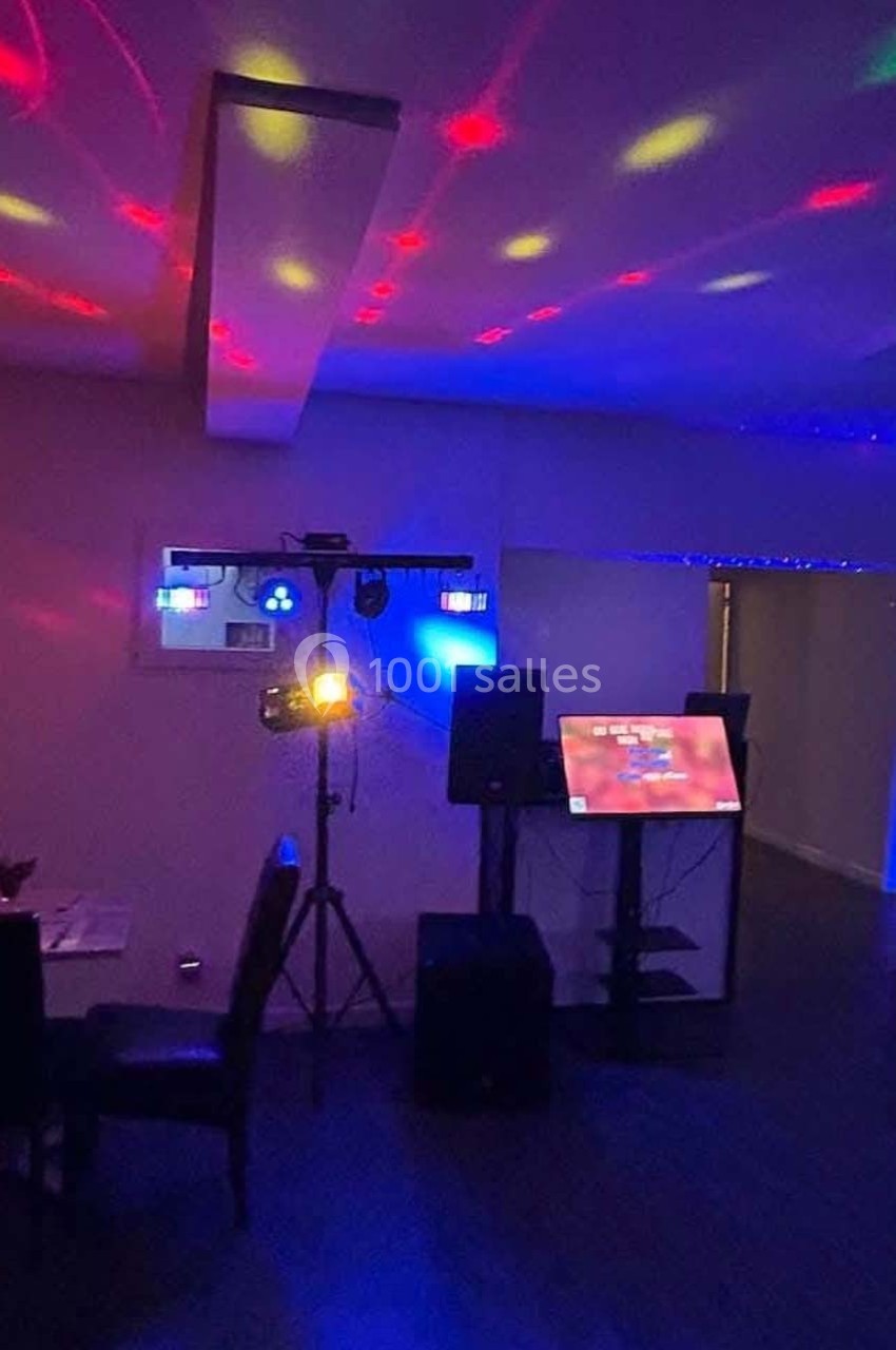 Salle sombre équipée de lumières colorées, d'un écran tactile, de haut-parleurs et d'un système d'éclairage.