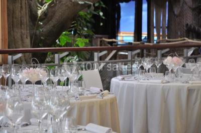Un groupe de personnes assises observe un aquarium géant avec des poissons et des requins, guidé par une animatrice.