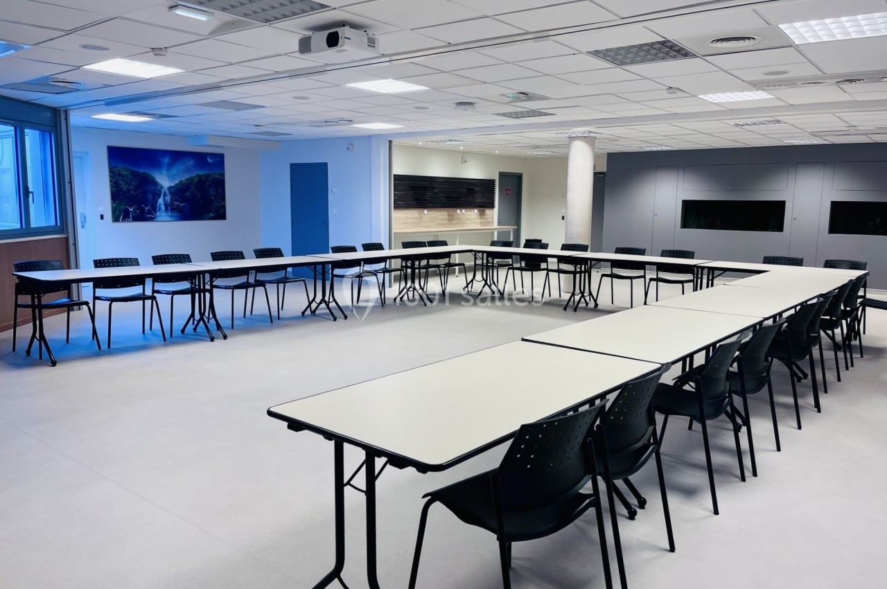 Location salle Montpellier (Hérault) - Planet Ocean Montpellier #1 Salle de réunion spacieuse avec tables disposées en U, chaises noires et éclairage naturel provenant d'une fenêtre.