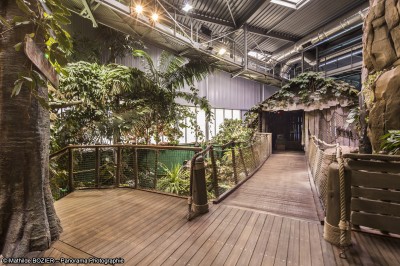 Un mannequin en combinaison d'astronaute près d'un buffet éclairé dans une salle à thème spatial.