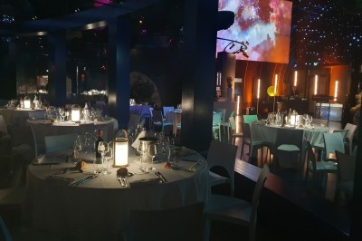 Un mannequin en combinaison d'astronaute près d'un buffet éclairé dans une salle à thème spatial.