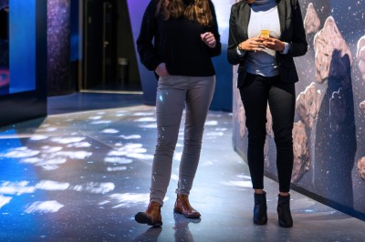 Un mannequin en combinaison d'astronaute près d'un buffet éclairé dans une salle à thème spatial.
