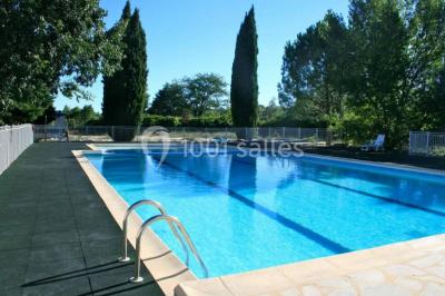 Des personnes en tenue de karaté pratiquent des exercices collectifs dans une salle aux murs en pierre et parquet en bois.
