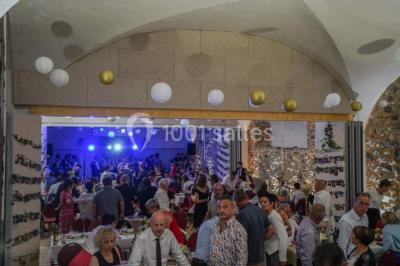 Des personnes en tenue de karaté pratiquent des exercices collectifs dans une salle aux murs en pierre et parquet en bois.