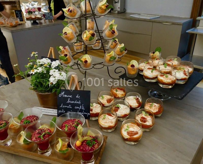 Buffet de verrines variées présentées sur une table, avec des fleurs décoratives et une ardoise descriptive.