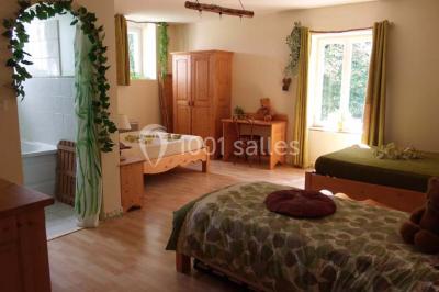 Chambre lumineuse avec murs jaunes, deux lits simples, décorations florales et une peluche sur un lit.