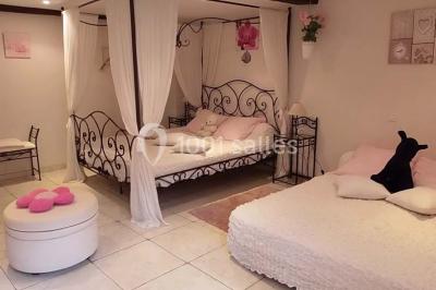 Chambre lumineuse avec murs jaunes, deux lits simples, décorations florales et une peluche sur un lit.