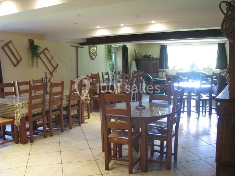 Salle à manger lumineuse avec tables en bois, chaises assorties et décoration murale rustique.