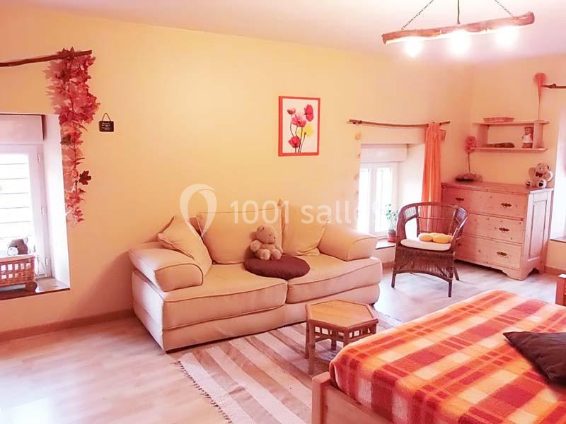 Salon chaleureux avec canapé beige, lit à carreaux rouges, meubles en bois clair et décoration automnale.