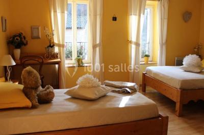 Chambre lumineuse avec murs jaunes, deux lits simples, décorations florales et une peluche sur un lit.