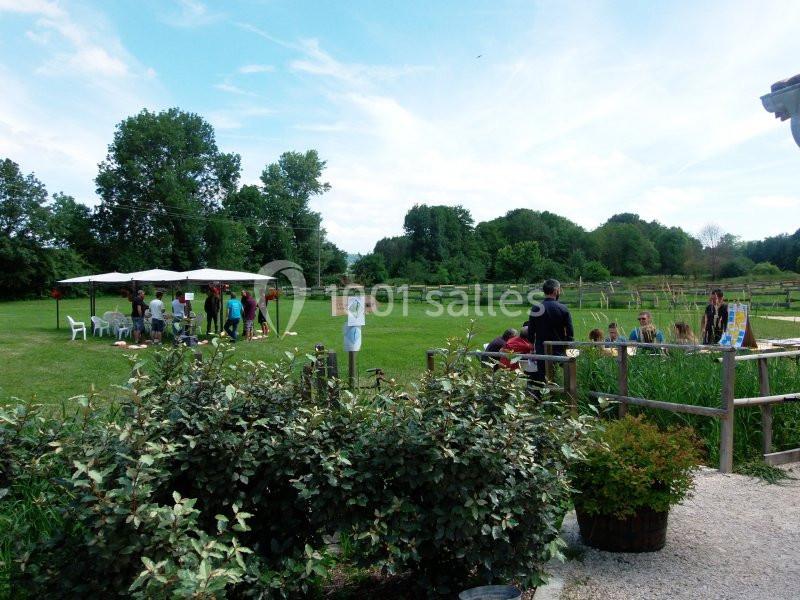 Un groupe de personnes participe à une activité en plein air dans un espace vert avec des tables et des parasols.