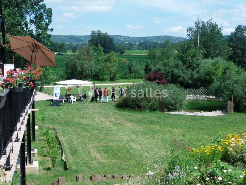 Groupe de personnes rassemblées près d'un étang dans un jardin verdoyant par une journée ensoleillée.
