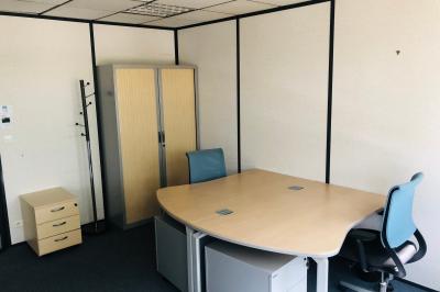 Façade d'un centre d'affaires en briques, avec une entrée bordée de végétation et des panneaux d'information.