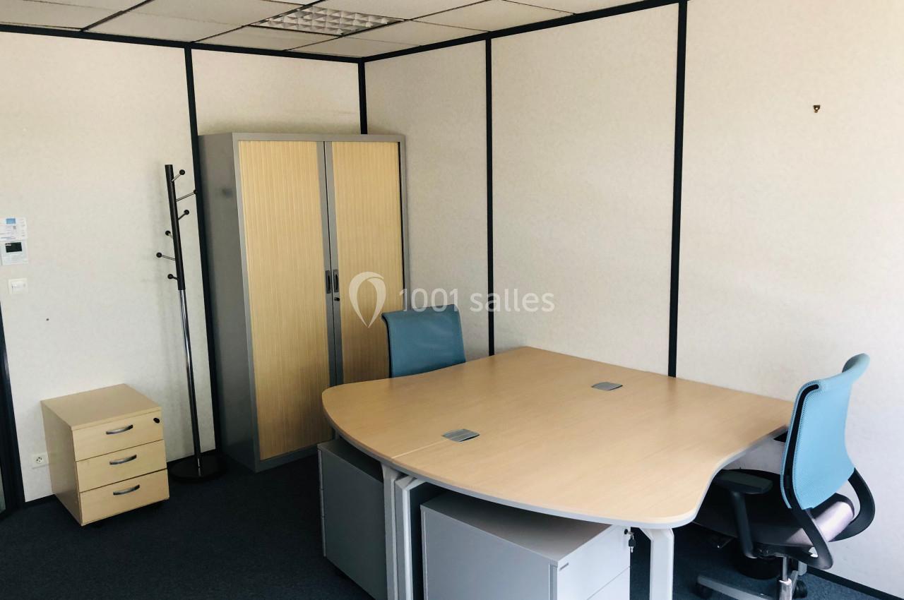 Bureau lumineux avec deux chaises, un bureau d'angle, une armoire en bois clair et un porte-manteau dans un espace fermé.