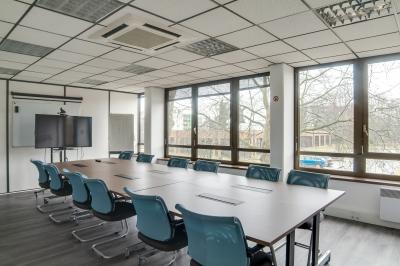 Façade d'un centre d'affaires en briques, avec une entrée bordée de végétation et des panneaux d'information.