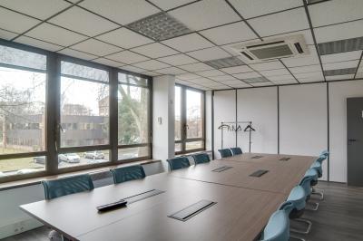 Façade d'un centre d'affaires en briques, avec une entrée bordée de végétation et des panneaux d'information.