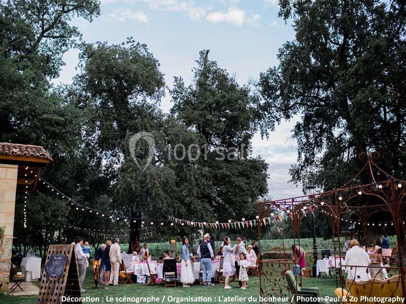 Personnes rassemblées dans un jardin décoré avec des guirlandes lumineuses, lors d'un événement en plein air.