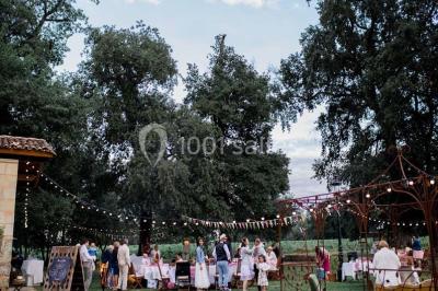Espace extérieur décoré avec guirlandes lumineuses, fauteuils et tonnelle, au crépuscule dans un jardin.