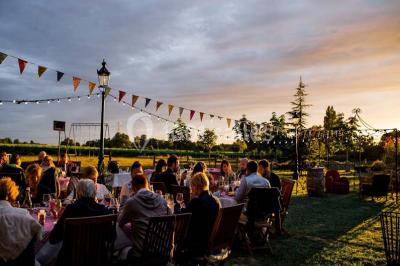 Espace extérieur décoré avec guirlandes lumineuses, fauteuils et tonnelle, au crépuscule dans un jardin.