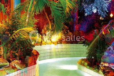 Salle de réception avec tables hautes noires, verres lumineux et éclairage tamisé dans une ambiance festive.