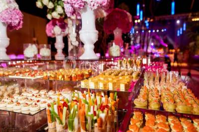 Salle de réception avec tables hautes noires, verres lumineux et éclairage tamisé dans une ambiance festive.