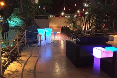 Salle de réception avec tables hautes noires, verres lumineux et éclairage tamisé dans une ambiance festive.