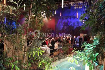 Salle de réception avec tables hautes noires, verres lumineux et éclairage tamisé dans une ambiance festive.