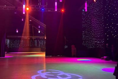 Salle de réception avec tables hautes noires, verres lumineux et éclairage tamisé dans une ambiance festive.