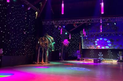 Salle de réception avec tables hautes noires, verres lumineux et éclairage tamisé dans une ambiance festive.