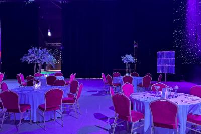 Salle de réception avec tables hautes noires, verres lumineux et éclairage tamisé dans une ambiance festive.