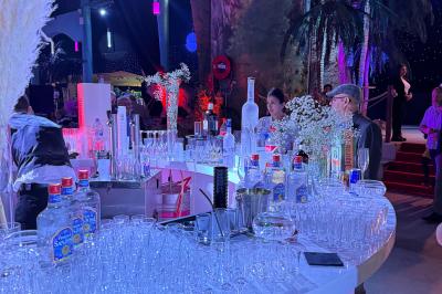 Salle de réception avec tables hautes noires, verres lumineux et éclairage tamisé dans une ambiance festive.