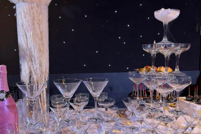 Salle de réception avec tables hautes noires, verres lumineux et éclairage tamisé dans une ambiance festive.