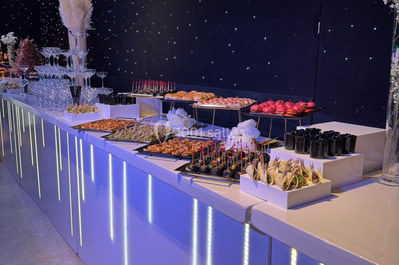 Buffet élégant avec une variété de plats et amuse-bouches disposés sur une table lumineuse dans un décor étoilé.
