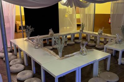 Salle de réception avec tables hautes noires, verres lumineux et éclairage tamisé dans une ambiance festive.