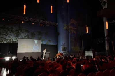 Salle de réception avec tables hautes noires, verres lumineux et éclairage tamisé dans une ambiance festive.