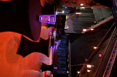 Salle de réception avec tables hautes noires, verres lumineux et éclairage tamisé dans une ambiance festive.