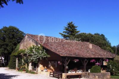 Terrains de tennis extérieurs entourés de verdure, avec des joueurs en action sous un ciel dégagé.