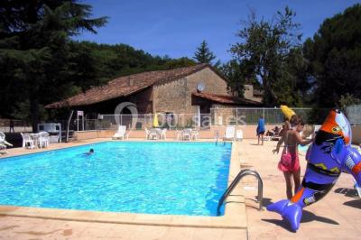 Terrains de tennis extérieurs entourés de verdure, avec des joueurs en action sous un ciel dégagé.