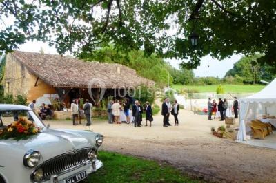 Terrains de tennis extérieurs entourés de verdure, avec des joueurs en action sous un ciel dégagé.