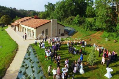 Terrains de tennis extérieurs entourés de verdure, avec des joueurs en action sous un ciel dégagé.