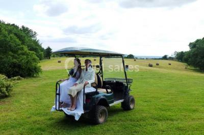 Terrains de tennis extérieurs entourés de verdure, avec des joueurs en action sous un ciel dégagé.