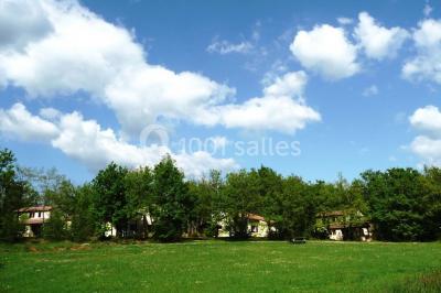 Un groupe de personnes assises en cercle en plein air, discutant près d'un tableau blanc, entouré d'arbres.